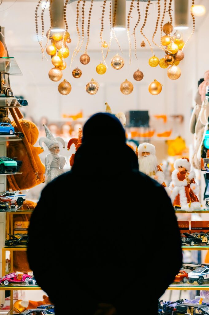 Silhouette of a person in front of a festive Christmas window display with golden ornaments.